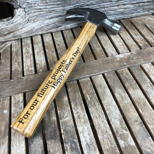 May include: A wooden-handled hammer with a black metal head. The handle is engraved with the text "For our future projects. Happy Father's Day!"