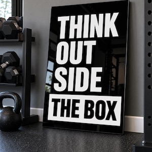 May include: A rectangular black wall sign with white bold sans-serif text that reads THINK OUT SIDE THE BOX. The word THE BOX is printed in black on a white rectangular background at the bottom of the sign, while the other words are white.