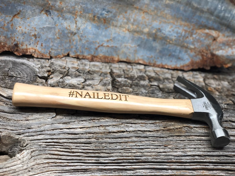 May include: A wooden-handled hammer with a black metal head. The handle is engraved with the text "#NAILEDIT".
