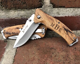 May include: Two pocket knives with wooden handles. One knife has the text "Love, Mom" engraved on the handle. The other knife has the initials "MBE" engraved on the handle.