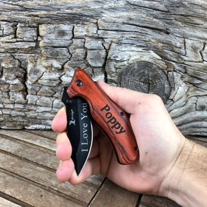 May include: A black pocket knife with a wooden handle. The handle is engraved with the words "Poppy" and "I Love You".