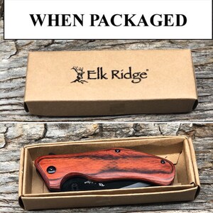 May include: A brown cardboard box with the text "Elk Ridge" printed on it. The box contains a red and black folding knife with a wooden handle.