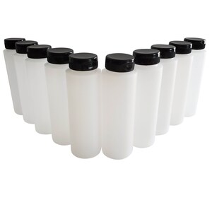 May include: Ten white plastic bottles with black screw-on lids. The bottles are arranged in a semi-circle.