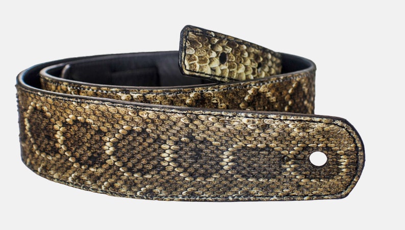 Puede incluir: Una correa de guitarra de cuero marr&oacute;n con un patr&oacute;n de piel de serpiente. La correa tiene un solo agujero para ajustar la longitud.