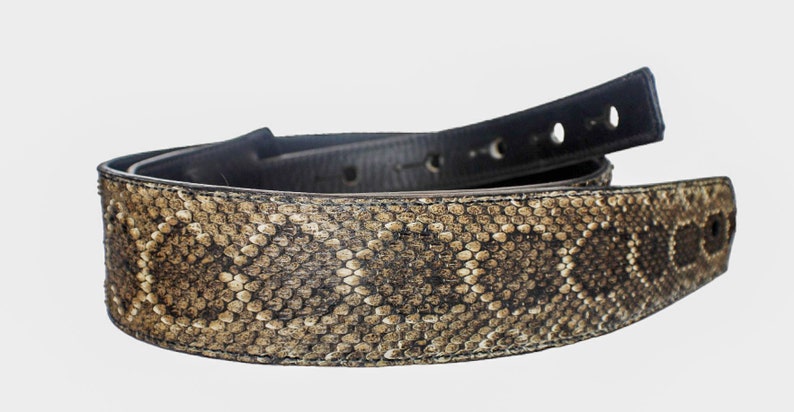 Puede incluir: Un cintur&oacute;n de cuero marr&oacute;n con un patr&oacute;n de piel de serpiente. El cintur&oacute;n est&aacute; doblado por la mitad y el lado de piel de serpiente est&aacute; mirando hacia la c&aacute;mara.