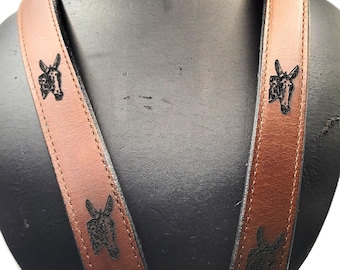 Tirantes de cuero, búfalo de agua y cabezas de mula grabados en las correas