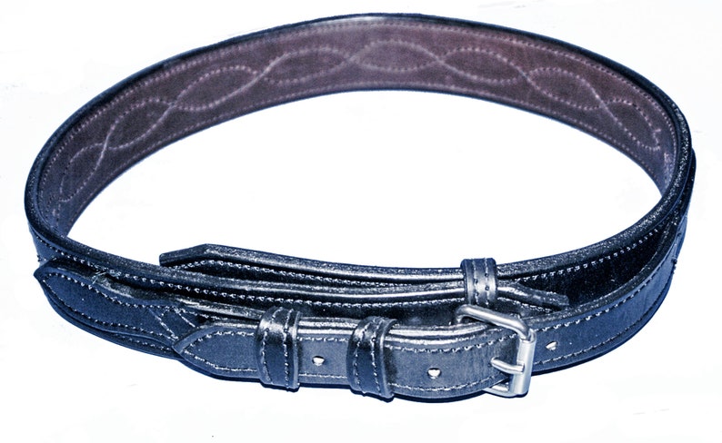 May include: A black leather belt with a silver buckle and a decorative pattern on the inside. The belt is folded in half and the buckle is visible.