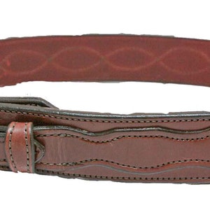 May include: A brown leather belt with a silver buckle and intricate stitching. The belt has a decorative design on the front and a smooth, brown leather lining.