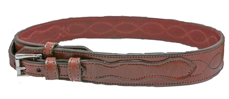 May include: A brown leather belt with a silver buckle and intricate stitching. The belt has a decorative design on the front and a smooth, brown leather lining.