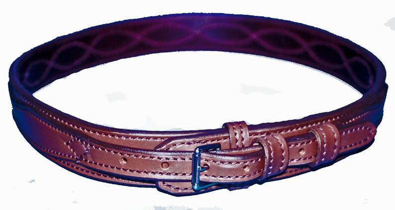 May include: A brown leather belt with a decorative stitching pattern and a silver buckle.
