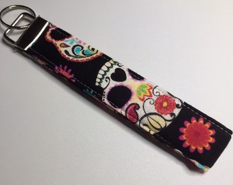 May include: Black key chain with a colorful sugar skull design.