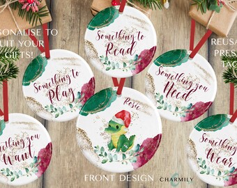 May include: Six round, white, ceramic gift tags with red and green watercolor designs. The tags have gold glitter accents and feature the text "Something to Read", "Something to Play", "Something you Want", "Something you Need", "Something to Wear", and "Rosie".