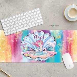 May include: A colourful desk mat featuring a mermaid, a seahorse and a dolphin in a seashell. The text "Steph" is written in purple at the top of the seashell.