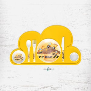 May include: A yellow cloud-shaped silicone placemat with a white plate, bowl, spoon, fork, and knife. The plate and bowl feature a construction theme with a yellow dumper truck and excavators. The plate has the name "Harley" printed on it.