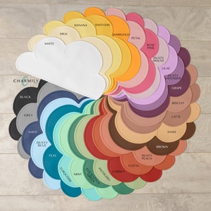 May include: A set of 24 silicone placemats in various colours, arranged in a circle. Each placemat is shaped like a cloud with a different colour and name printed on it. The colours include white, black, grey, navy, teal, turquoise, mint, eucalyptus green, pistachio, garnet, cotta, dusty peach, brown, sand, latte, biscuit, grape, dusty lavender, lilac, dusty mauve, rose pink, petal, marigold, daffodil, banana, and milk.