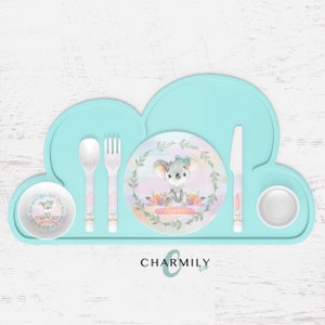 May include: A light blue silicone placemat shaped like a cloud with a white plate, bowl, and cup. The plate features a watercolour design of a koala with flowers and the word "Ava" written on it. The set also includes a white spoon, fork, and knife.