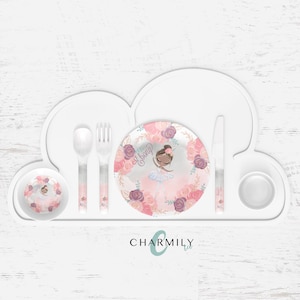 Puede incluir: Un plato blanco dividido en forma de nube con un diseño floral rosa y morado que presenta una bailarina con el nombre "Ebony" en el plato. El juego incluye un tazón a juego, una cuchara, un tenedor y un cuchillo.