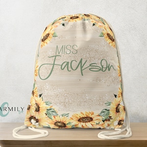 May include: A beige drawstring bag with a sunflower design and the name "Miss Jackson" in green script. The bag features a border of yellow sunflowers with green leaves and a cream-colored drawstring.