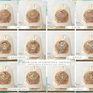Puede incluir: Ocho mochilas de cordón personalizadas con diferentes animales australianos, incluyendo un emú, un cacatúa, un canguro, un koala, un kookaburra y un numbat. Cada mochila tiene un tema navideño festivo con un gorro de Papá Noel rojo en el animal y una corona de vegetación. Las mochilas son todas blancas con un cordón beige.