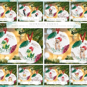May include: Set of 10 round Christmas ornaments featuring Australian animals. Each ornament is white with a watercolor-style illustration of an animal, including a bilby, black cockatoo, blue heeler, cockatoo, crocodile, dingo, echidna, emu, galah, and kangaroo. Each ornament has a red and green background with gold glitter accents. The ornaments are personalized with the names "Rosie" and "Neal".