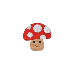 Puede incluir: Parche de hongo bordado con gorro rojo y lunares blancos. El hongo tiene un tallo marrón y una cara sonriente. El parche es probablemente para ropa o accesorios.