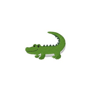 May include: An embroidered patch featuring a green alligator with a curved tail, dark green scales along its back, black eyes, and a white underbelly. The design is rendered in a textured stitch pattern, showcasing the creature in profile.