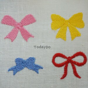 May include: Four embroidered bows in pink, yellow, blue, and red on a white fabric background. The bows are stitched with a textured thread, and the word "TodayDo" is printed in the center.