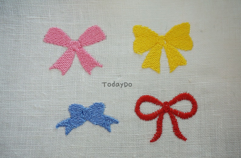 May include: Four embroidered bows in pink, yellow, blue, and red on a white fabric background. The bows are stitched with a textured thread, and the word "TodayDo" is printed in the center.