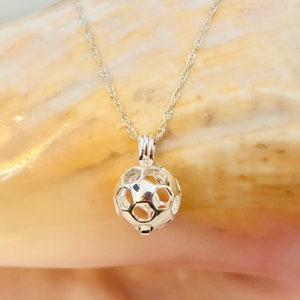 May include: A silver chain necklace with a silver cage pendant shaped like a soccer ball.
