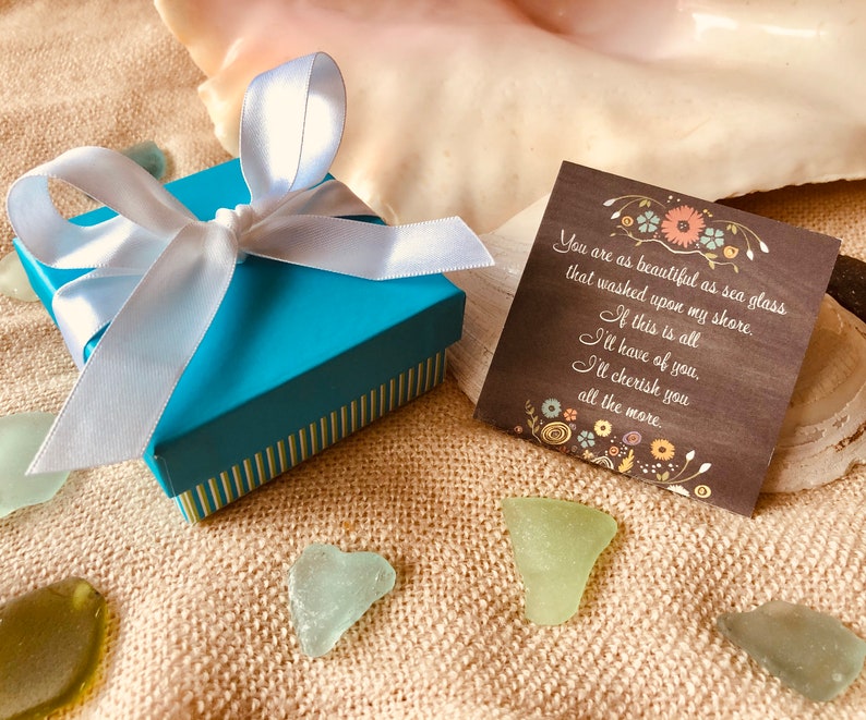 Pu&ograve; includere: Una scatola regalo blu turchese con un nastro di raso bianco e un fiocco. La scatola &egrave; appoggiata su una superficie di juta marrone con vetro di mare sparso intorno. Un piccolo biglietto con un messaggio scritto a mano &egrave; accanto alla scatola. Il messaggio dice: "Sei bella come il vetro di mare che &egrave; stato portato a riva. Se questo &egrave; tutto ci&ograve; che avr&ograve; di te, ti amer&ograve; ancora di pi&ugrave;."