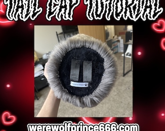 May include: A gray faux fur tail cap with black straps and a black label that says "Werewolf Prince" with a paw print. The tail cap is held in a person's hand.