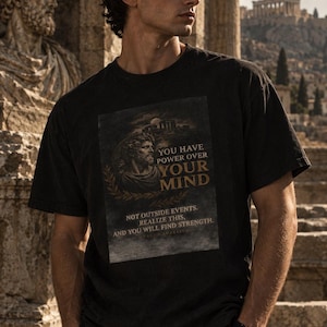 May include: A black short-sleeved t-shirt featuring a graphic print of a classical bust and the text: YOU HAVE POWER OVER YOUR MIND NOT OUTSIDE EVENTS. REALIZE THIS, AND YOU WILL FIND STRENGTH. MARCUS AURELIUS. The design includes a laurel wreath.