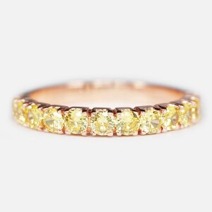 May include: A delicate gold band ring with a row of small, round, yellow diamonds.