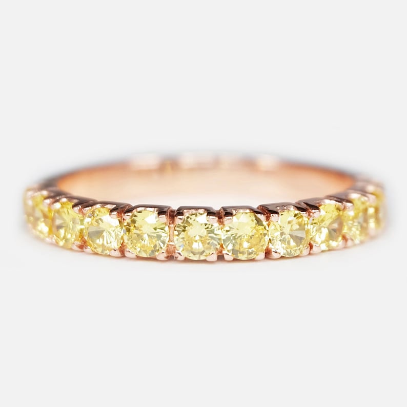 May include: A delicate gold band ring with a row of small, round, yellow diamonds.