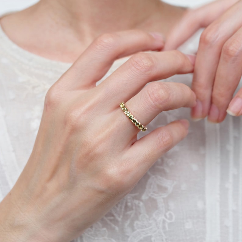 May include: A gold band ring with a textured design. The ring is worn on a person's finger.