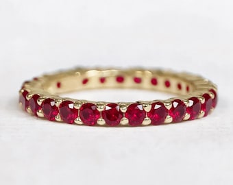Può includere: Un anello a fascia eternity con una fila continua di rubini rossi taglio rotondo incastonati in una banda in oro giallo lucido. Il design circolare presenta molteplici pietre preziose sfaccettate fissate da piccole griffe in oro.