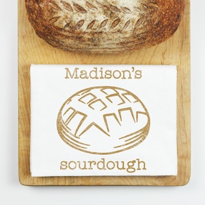 May include: A white kitchen towel with the text "Madison's sourdough" and a brown line drawing of a loaf of bread.
