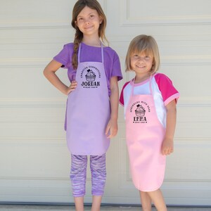 two young girls wearing personalized cupcake baking aprons