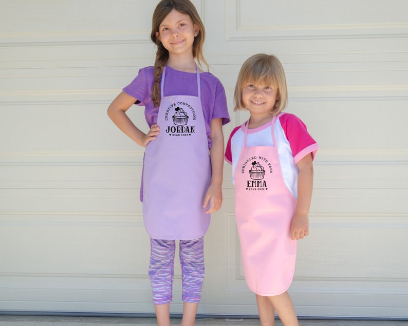 two young girls wearing personalized cupcake baking aprons