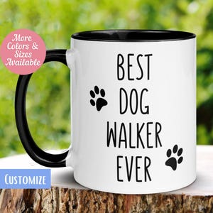 May include: White ceramic mug with a black interior and handle. The mug features the text "BEST DOG WALKER EVER" in black, along with paw print graphics. The mug has a pink circle with the text "More Colors & Sizes Available" and a blue rectangle with the word "CUSTOMIZE".