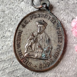 Peut inclure: Pendentif ovale argenté antique avec une image détaillée d'un homme en chapeau et robe. L'inscription "J.C. PERBOYRE PRIEZ POUR NOUS" entoure le bord. Une petite boucle est présente en haut pour l'accrocher.