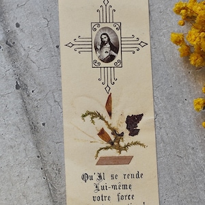 May include: Vintage bookmark featuring an image of Jesus within a decorative cross design. The bookmark includes dried plant elements and French text: "Qu'Il se rende Lui-même votre force et votre soutien!" (May He make Himself your strength and your support!).