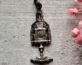 May include: Silver charm in the shape of a gothic style church with a detailed design. The charm has a loop at the top for attaching to a necklace or bracelet.