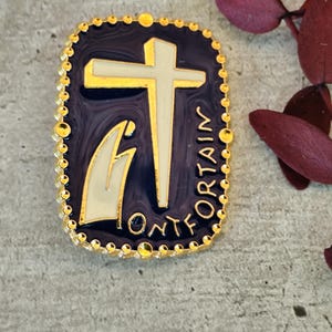 Puede incluir: Un pin rectangular con borde dorado y fondo azul oscuro. El pin presenta una cruz dorada y una figura blanca y dorada. La palabra "FONTAIN" está escrita en oro alrededor del borde del pin.