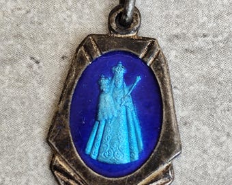 Puede incluir: Colgante vintage plateado con centro de esmalte azul. El colgante presenta una imagen religiosa de dos figuras con túnicas azul claro. El colgante tiene forma rectangular con borde decorativo y un lazo para una cadena.