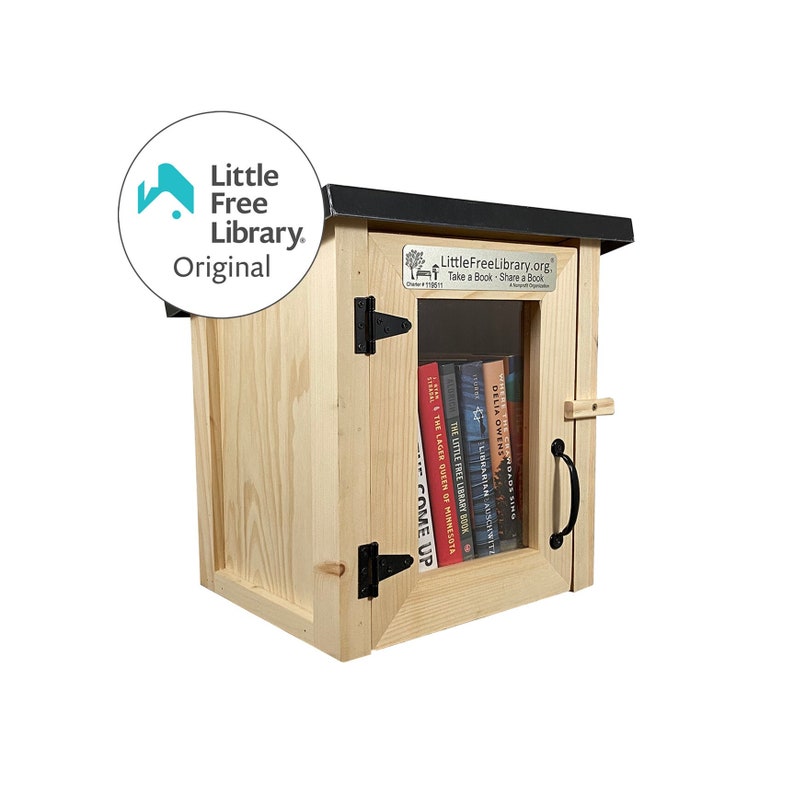May include: A wooden Little Free Library with a black roof and a glass door. The door has a black metal hinge and a black metal handle. The library is filled with books. The text on the library reads "LittleFreeLibrary.org Take a Book Share a Book".