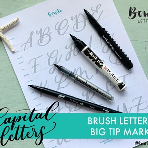 May include: A white sheet with capital letters in a calligraphy style, with four black brush tip markers and a starfish. The sheet has the text "Bondi Letters" and "Brush Lettering Big Tip Markers".