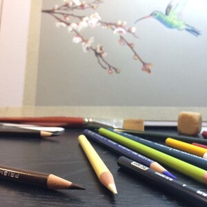May include: A close-up of a variety of colored pencils and a paintbrush on a black surface. The pencils are arranged in a fan shape, with the tips of the pencils pointing towards the viewer. The pencils are all different colors, including black, brown, green, yellow, and red. The paintbrush is made of natural bristles and has a wooden handle. The pencils and paintbrush are used for drawing and painting.