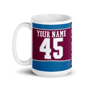 May include: White ceramic mug with a burgundy and blue design. The mug has the text "YOUR NAME 45" printed on it.