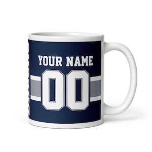 May include: White ceramic mug with a blue and gray design. The mug features a white number "00" and the text "YOUR NAME".